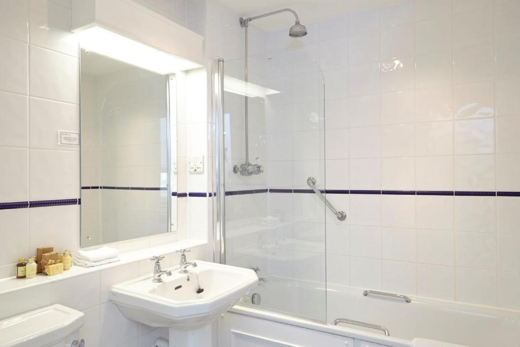 a white bathroom with a sink and a shower at The Royal Hotel in Ventnor