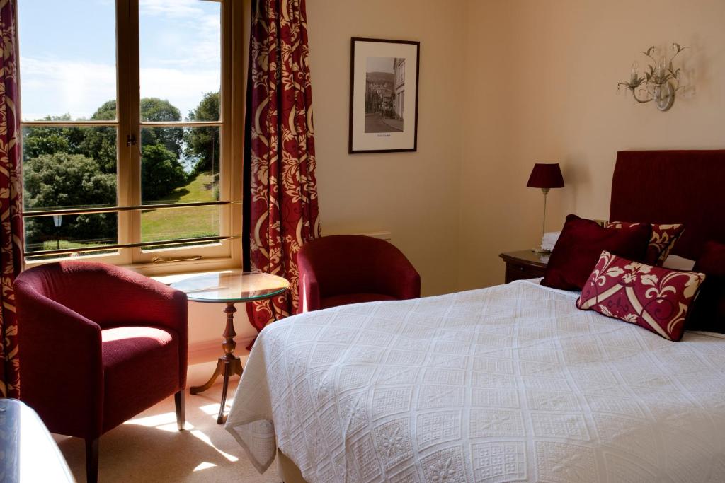 a bedroom with a bed and two chairs and a window at The Royal Hotel in Ventnor