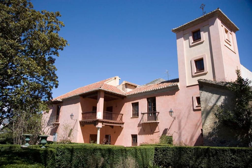 a large pink building with a tower and a fence at Casa Mosaico Granada en el V de Lecrin in Nigüelas