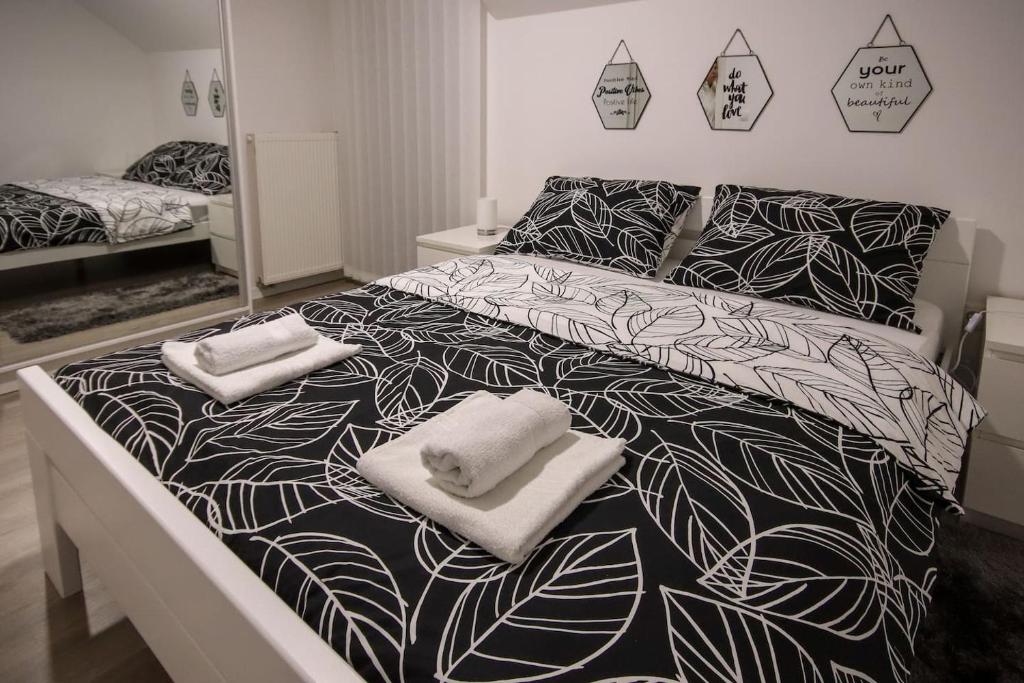 a black and white bed with two towels on it at Apartman F&F in Otočac
