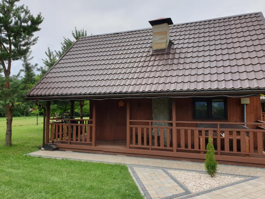 a large wooden house with a deck in a yard at Domki nad Sanem in Lesko