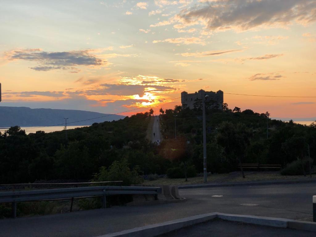 um castelo numa colina com o pôr-do-sol ao fundo em Apartment Zeljkica - Villa Sunce em Senj