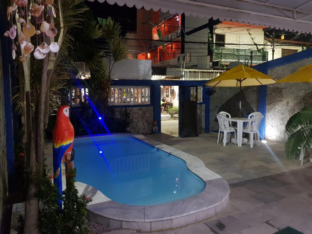a pool at night with a parrot statue next to it at Pousada Mananauê Beach in Porto De Galinhas