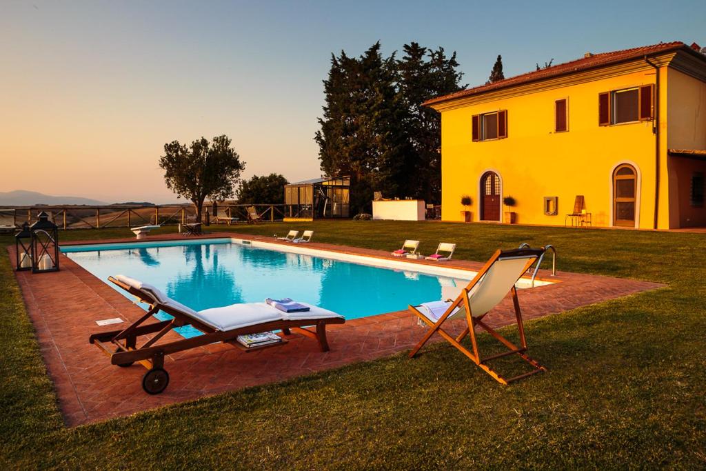 a swimming pool with a chair and a house at Il Montelletto in Santa Luce