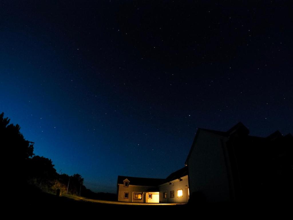 a house with lights on in the night sky at The Skellig Lodge & Hostel in Ballinskelligs