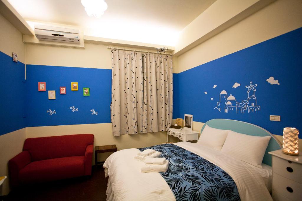 a bedroom with blue walls and a bed and a red chair at Sweet Rainbow B&amp;B in Hualien City