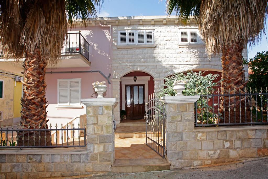 a house with a gate and two palm trees at Apartment Ambroz in Vela Luka