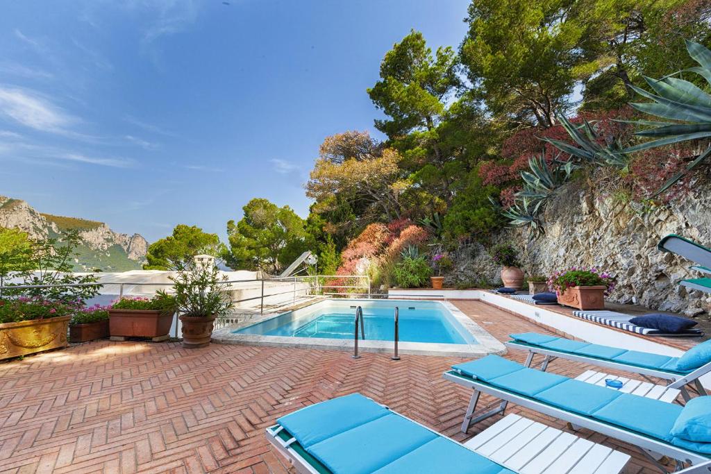 una piscina con tumbonas azules y una casa en Amore Rentals - Villa Polifemo en Capri