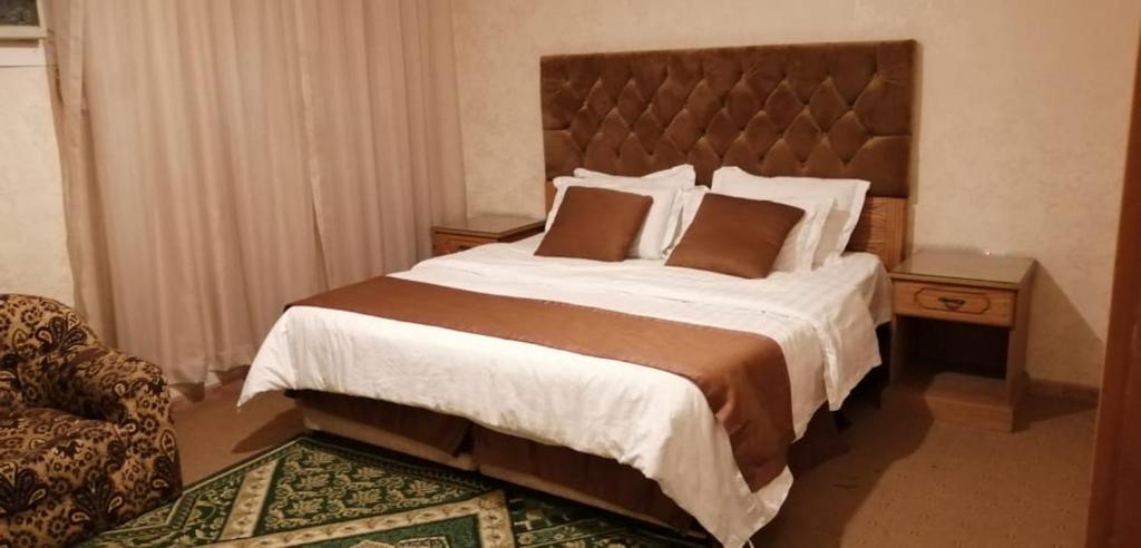 a bedroom with a large bed and a chair at Dar Al Riyadh Apartments in Riyadh