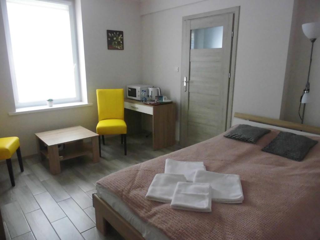 een slaapkamer met een bed, een bureau en een gele stoel bij Bezowy pokój in Jedlina-Zdrój