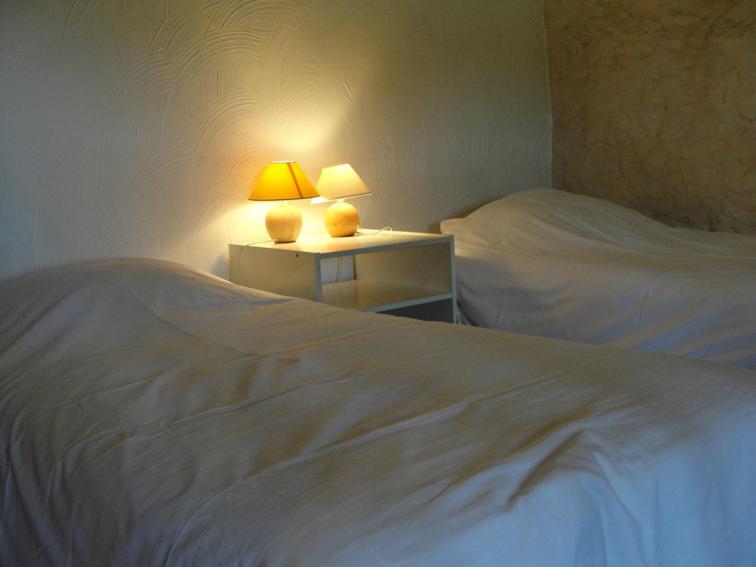two beds in a room with a table with two lamps at Le Mas De La Chérine in Quinson