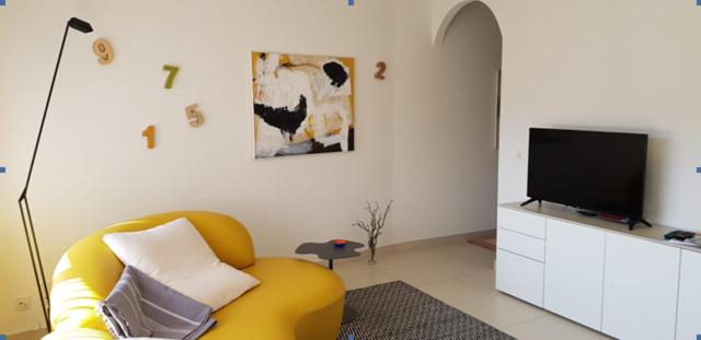 un soggiorno con sedia gialla e TV a schermo piatto di GRETA 29 a Losone