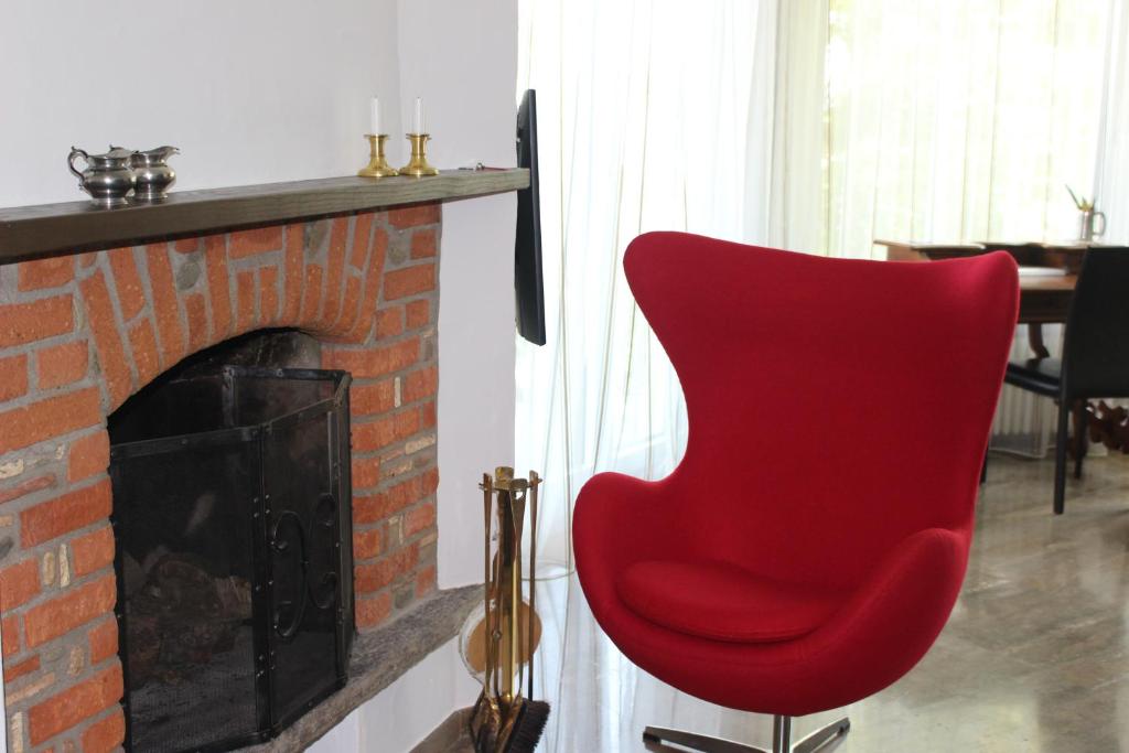 a red chair sitting in front of a fireplace at Casa Creavita in Cademario