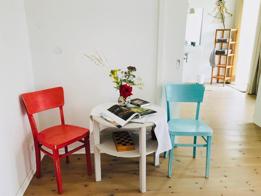 a table with three chairs and a vase with flowers on it at Alte Schlossgärtnerei in Plön