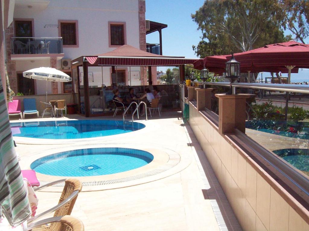 a swimming pool with two chairs and a building at Aybey Apart Hotel in Turgutreis