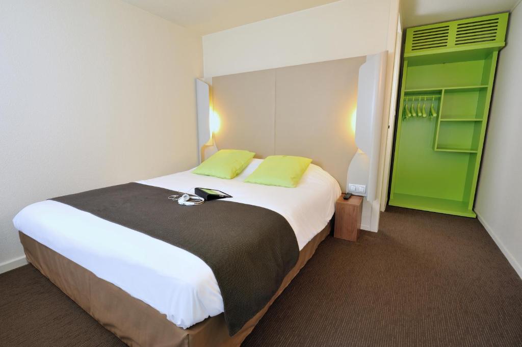 a bedroom with a large white bed with green accents at Campanile Lorient - Lanester in Lanester