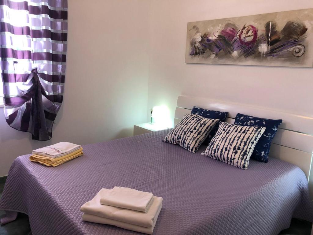 a bedroom with a purple bed with two towels on it at villa per sole mare e relax in Alcamo Marina
