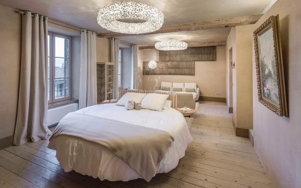 una camera con un grande letto bianco e un soggiorno di Ancienne fabrique de soie À la Galicière a Chatte