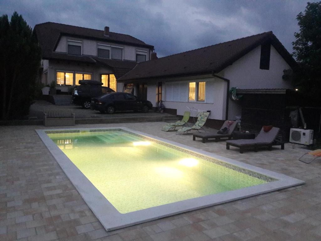 a swimming pool in front of a house at night at Respect Apartament in Hévíz