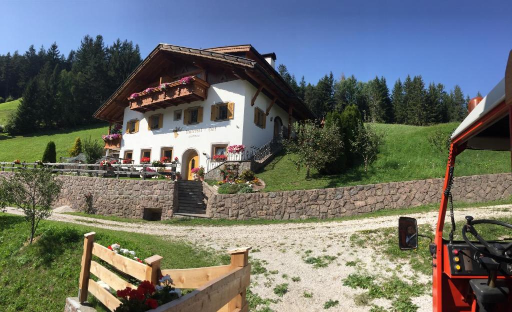 a white house with a brown roof on a hill at Untertalhof in Castelrotto