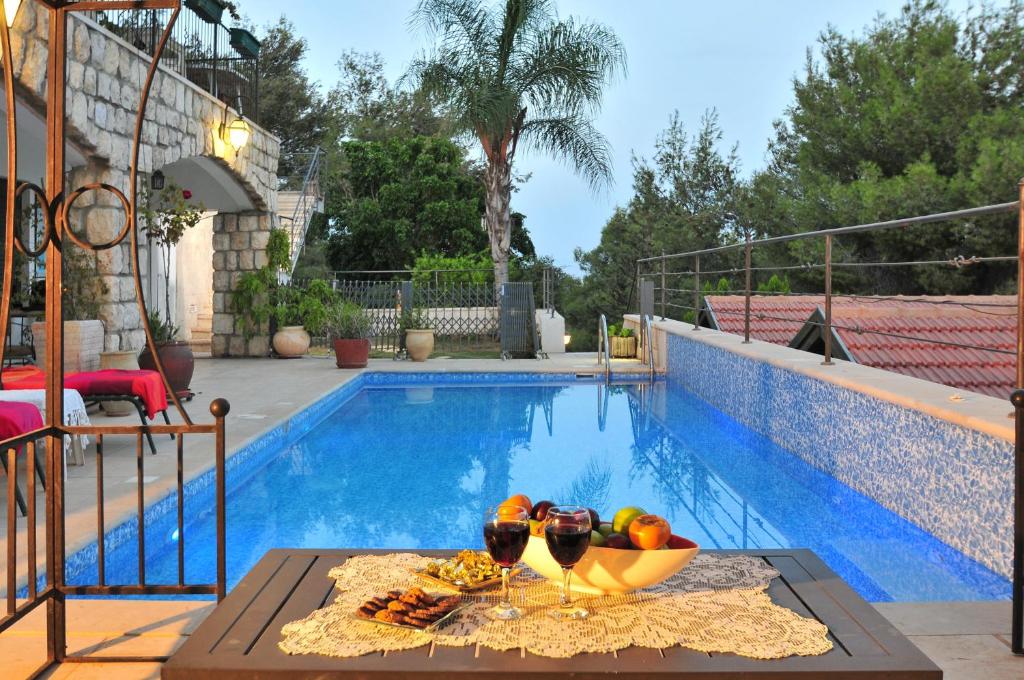 a table with a bowl of fruit next to a swimming pool at Bikta Banof in Rosh Pinna