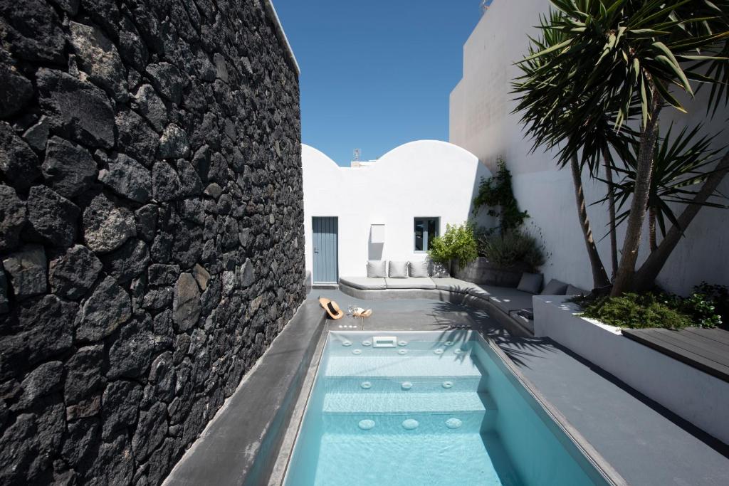einen Pool vor einem Haus mit einer Steinmauer in der Unterkunft Onirondas Villas in Fira