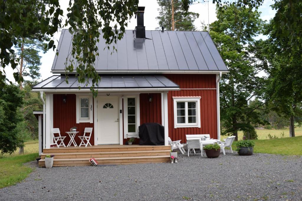 a red tiny house with a porch and chairs at Countryside Villa Skogsbacka in Tammisaari