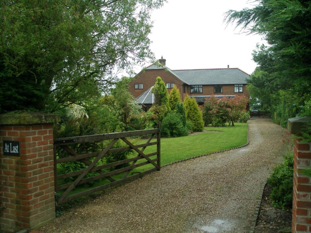 a fence in front of a house with a driveway at At Last Bed & Breakfast in Edlington