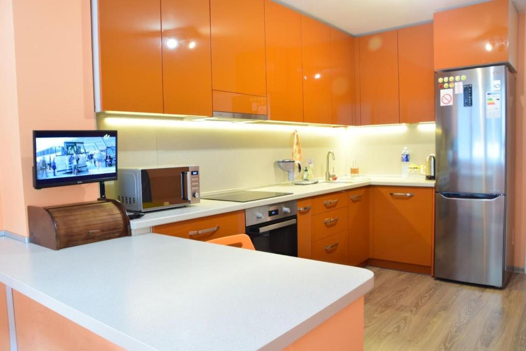 a kitchen with orange cabinets and a stainless steel refrigerator at Apartment Visagina in Visaginas