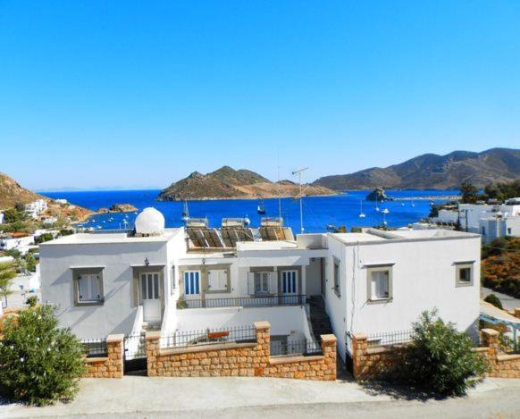 a large white house with the ocean in the background at Captain Manos Studio Apartments in Grikos