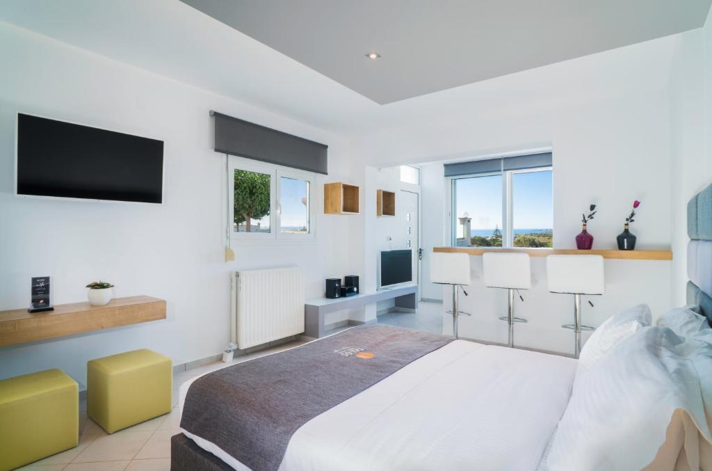 a white bedroom with a bed and a flat screen tv at Talos Luxury Suites in Kounoupidhianá