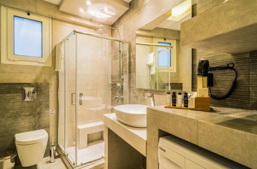 a bathroom with a sink and a shower and a toilet at Talos Luxury Suites in Kounoupidhianá