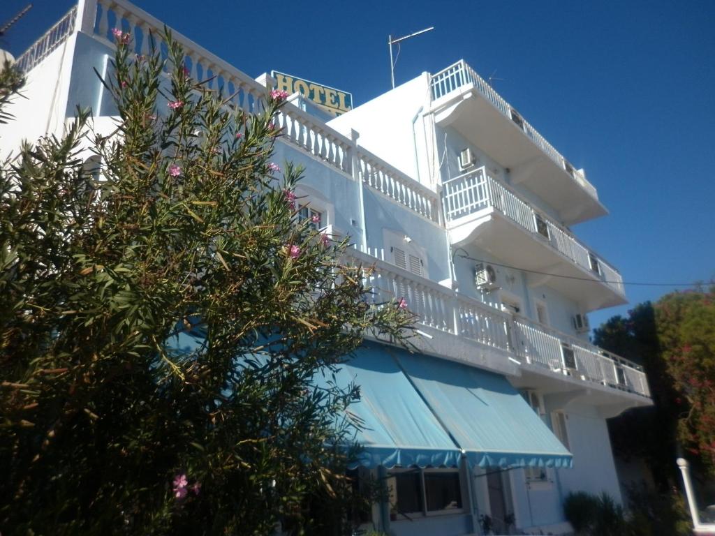 a white building with a balcony and a tree at Miramare Hotel in Lakkíon