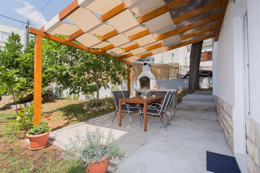 patio con tavolo e sedie sotto un pergolato di Apartments Pinery a Makarska