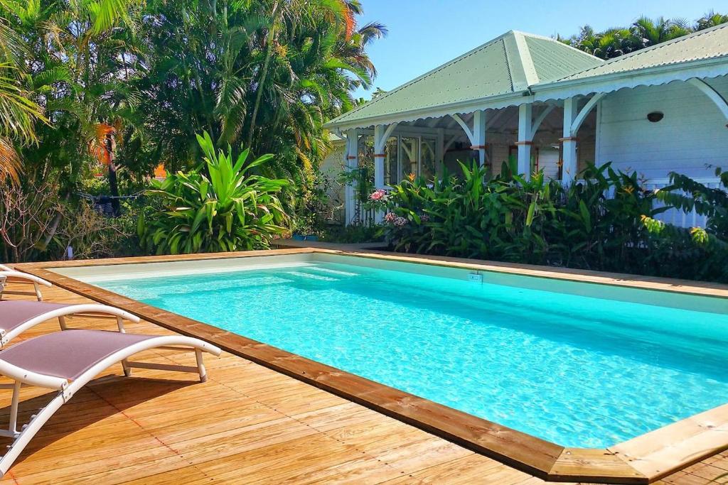 uma piscina com duas cadeiras e uma casa em Villa Mabouya Fort Royal em Deshaies