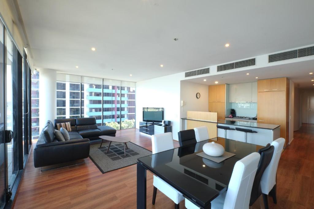 a living room with a dining table and a kitchen at ACD Apartments in Melbourne