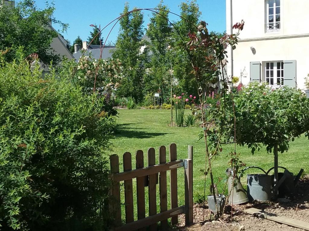 un jardin avec une clôture en bois dans une cour dans l'établissement Chambre d'hôte le 18-20, à Saint-Martin-des-Entrées