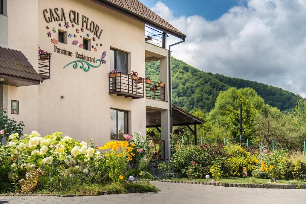a building with a balcony with flowers on it at Pensiunea Casa cu Flori in Cisnădioara
