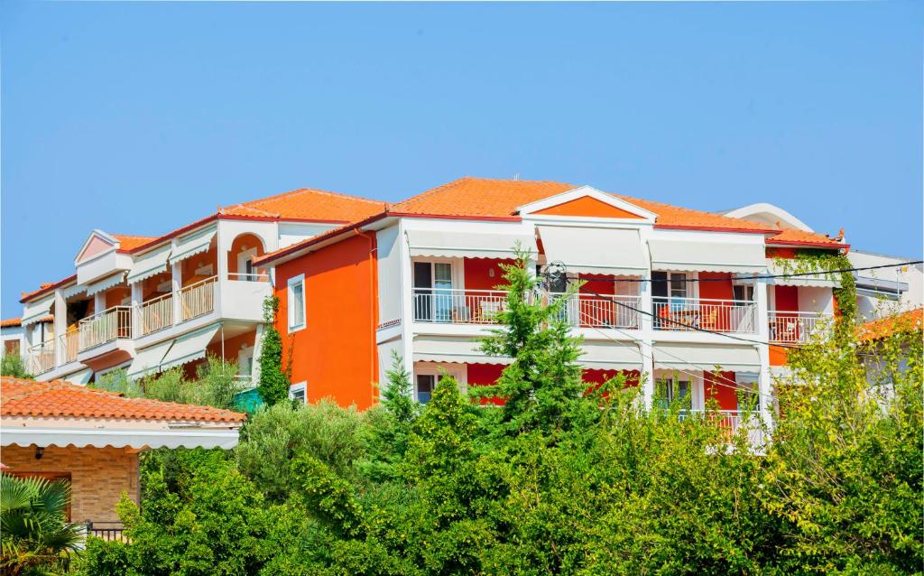 un edificio naranja y blanco con árboles en el primer plano en Summer House, en Nikiti