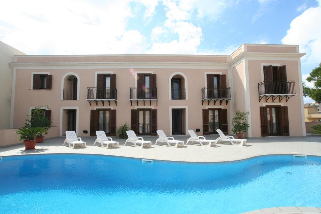 eine Villa mit einem Pool, Stühlen und einem Haus in der Unterkunft Moresco Resort in Lampedusa