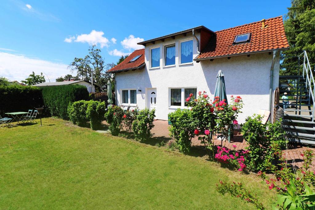 a white house with a garden and an umbrella at Fewo Urlaubsidyll 1_GUeTH in Ostseebad Karlshagen