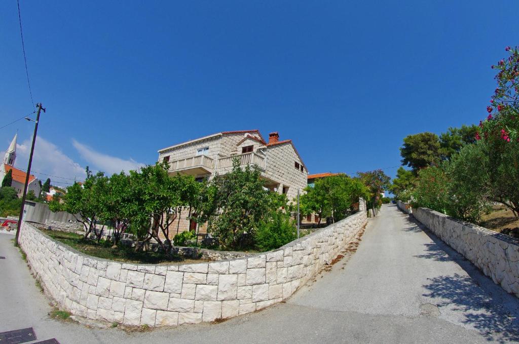 a stone wall next to a street with a house at Large and charming apartment near beach with big & sunny terrace in Sumartin