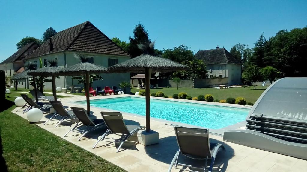 a group of chairs and umbrellas next to a swimming pool at Le Domaine des Papillons in Beaujeu-Saint-Vallier-et-Pierrejux