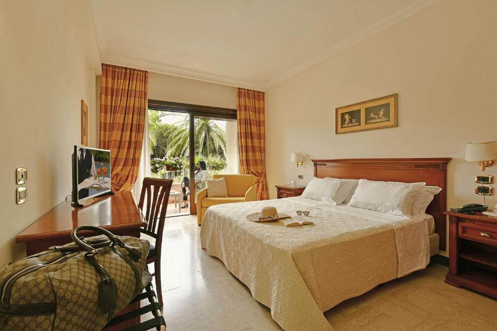 sypialnia z łóżkiem, biurkiem i telewizorem w obiekcie Minerva Resort Hotel w mieście Paestum