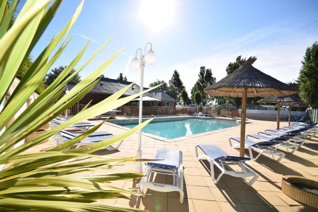 a swimming pool with lounge chairs and umbrellas at Domaine MON CALME in Piriac-sur-Mer