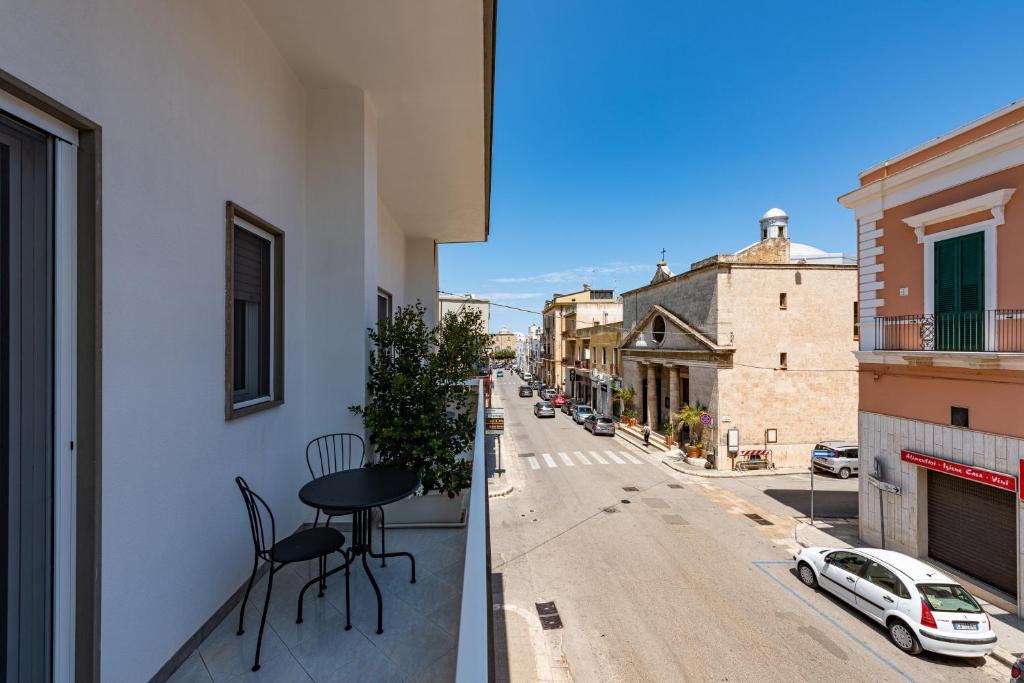 a balcony with a table and chairs on a city street at Sinestesia in Polignano a Mare