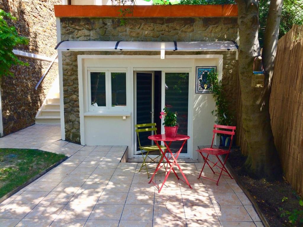un patio con mesa y sillas frente a un garaje en SUITE AVEC TERRASSE ET JARDIN AUX PORTES DE PARIS, en Les Pavillons-sous-Bois