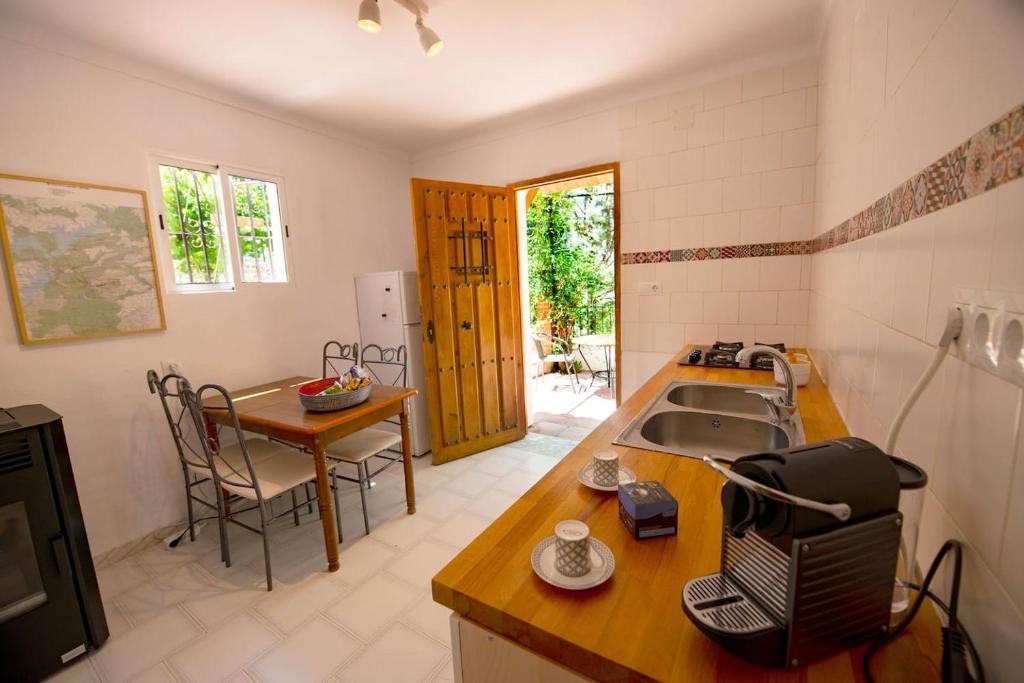 uma cozinha com um lavatório e uma mesa com uma mesa; em Bonita casa con vistas El Chorro em El Chorro