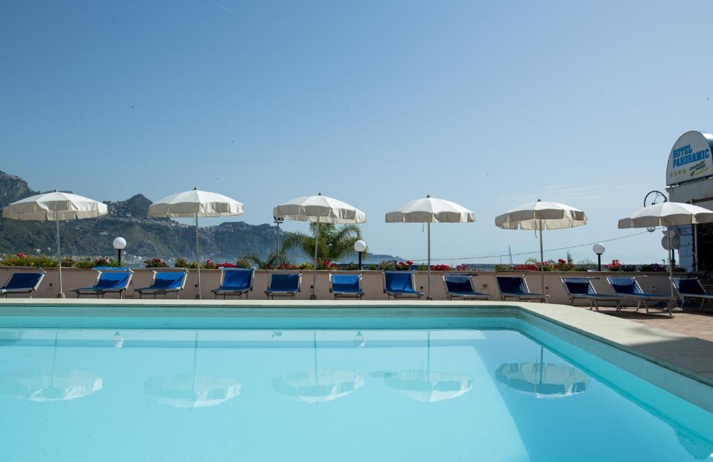 a swimming pool at a hotel with chairs and umbrellas at Hotel Panoramic in Giardini Naxos