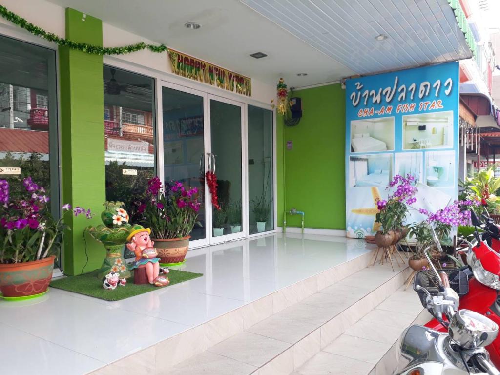ein Geschäft mit grünen Wänden und Blumen davor in der Unterkunft Cha-Am Fish Star in Cha-am